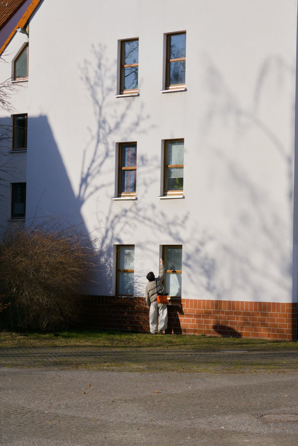 A person cleans the exterior window of a modern house.