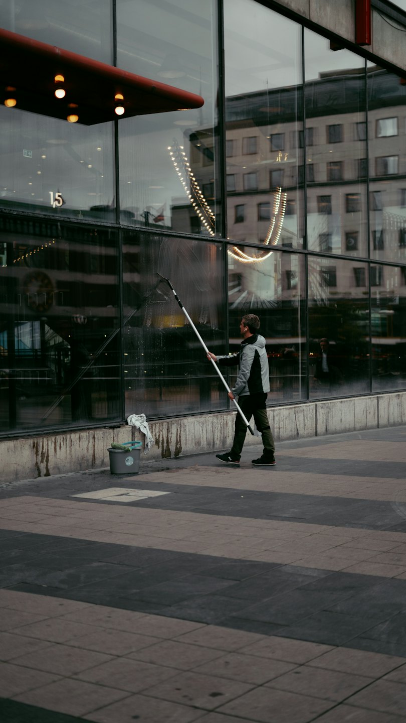 Man cleaning large glass building windows with squeegee.