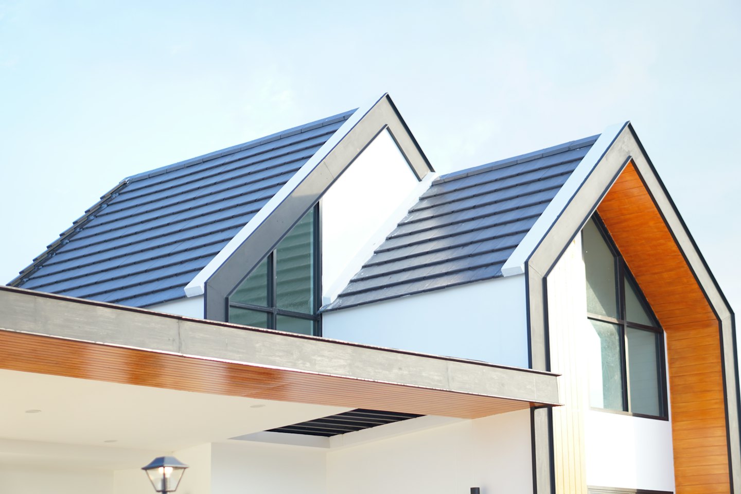Modern house with white walls and wood accents under a clear sky.