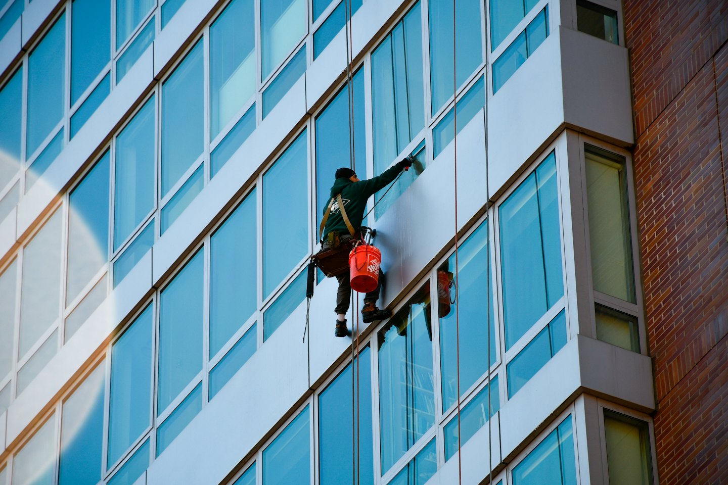 Window cleaner suspended on ropes washing a high-rise building.